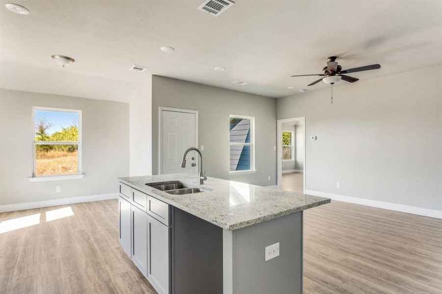 Kitchen featuring light stone countertops, gray cabinetry, light wood-style flooring, and recessed lighting