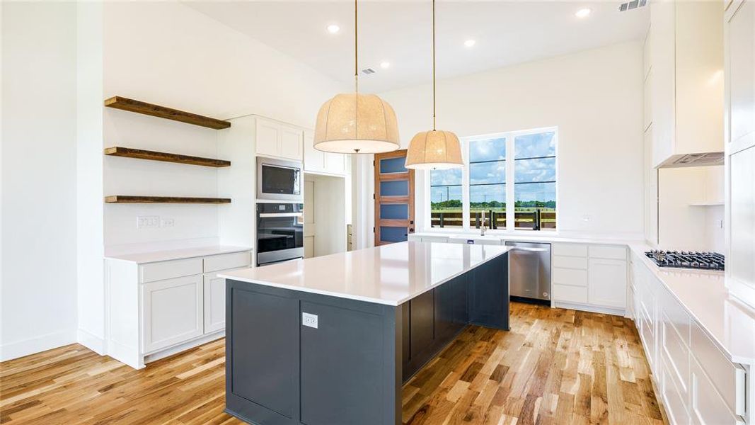 Kitchen featuring light hardwood / wood-style floors, a kitchen island, white cabinetry, and appliances with stainless steel finishes