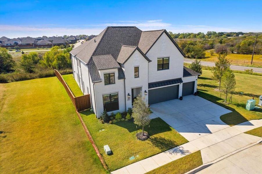 View of front of house featuring a garage, a shingled roof, fence, driveway, and a front lawn