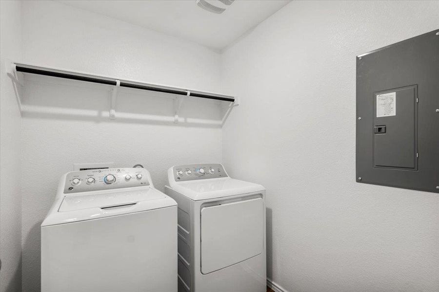 Laundry area featuring electric panel, separate washer and dryer, and a textured wall