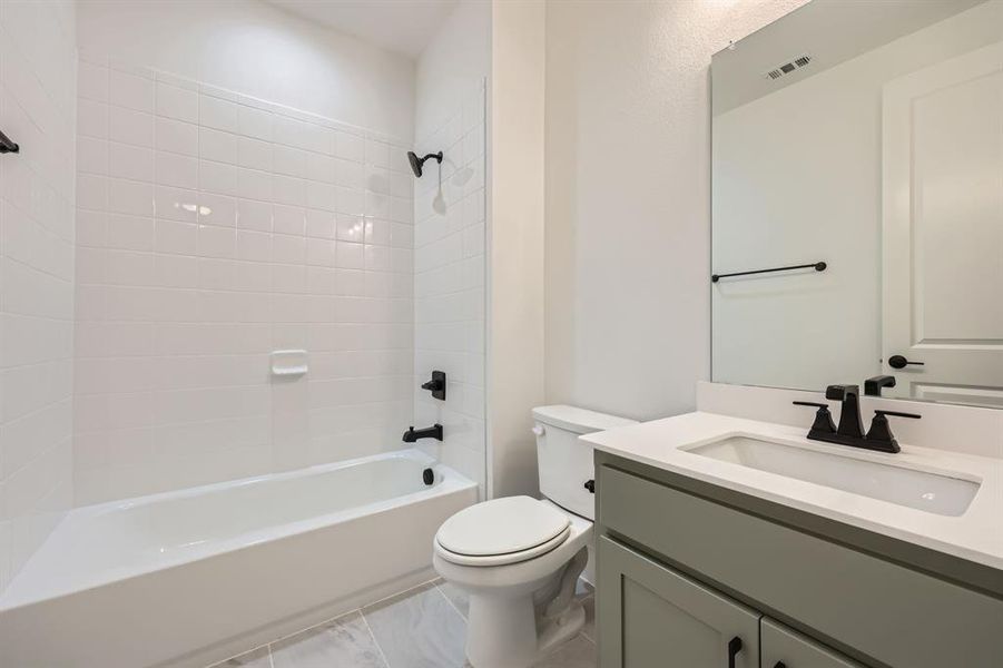 Full bathroom featuring toilet, vanity, and tiled shower / bath