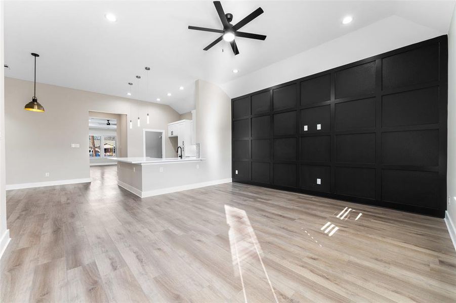 Unfurnished living room with a high ceiling, ceiling fan, and light wood-type flooring