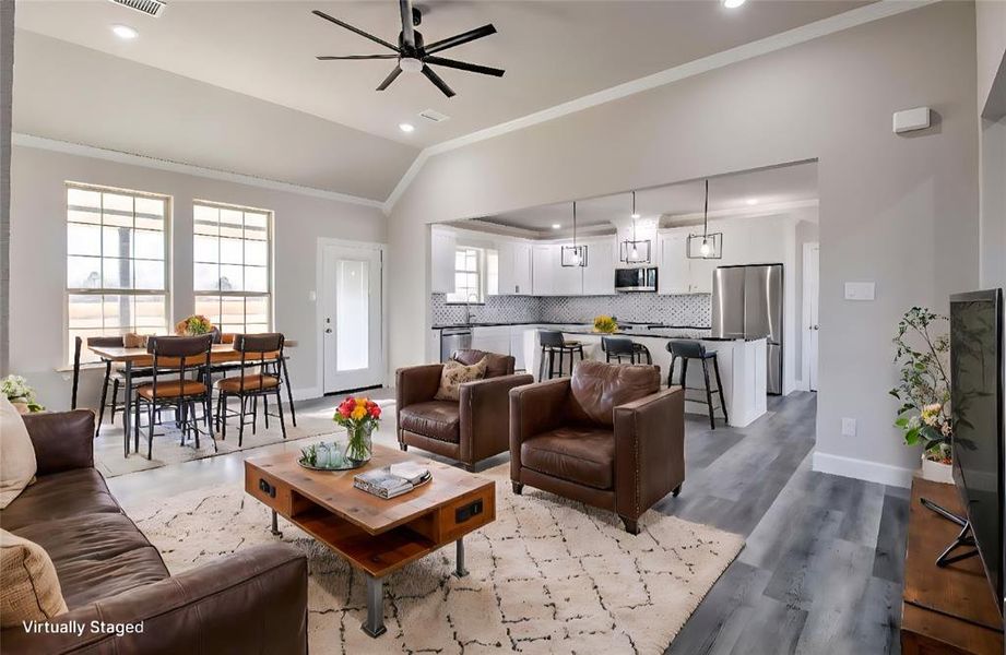 Living room featuring ornamental molding, vaulted ceiling, ceiling fan, dark wood-style floors, and recessed lighting