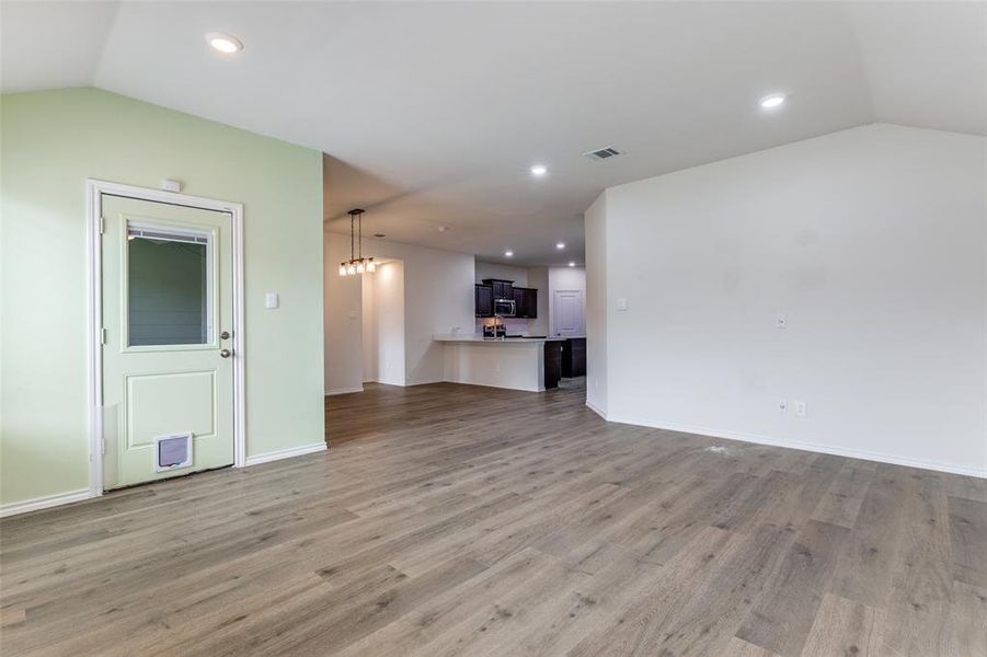 Open concept living area featuring wood-finish flooring, recessed lighting, and a vaulted ceiling Open concept living area featuring wood-finish flooring, recessed lighting, and a vaulted ceiling