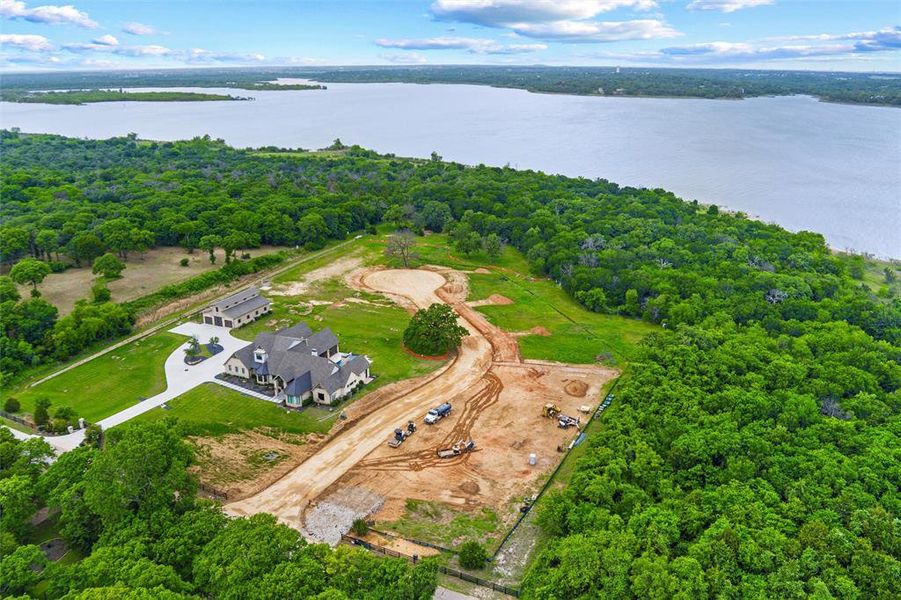 Expansive property featuring a large residence with a circular drive, a separate multi-car garage building, and significant undeveloped land Expansive property featuring a large residence with a circular drive, a separate multi-car garage building, and significant undeveloped land