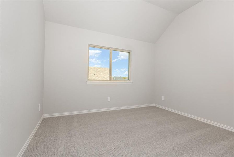 Carpeted spare room with baseboards and lofted ceiling