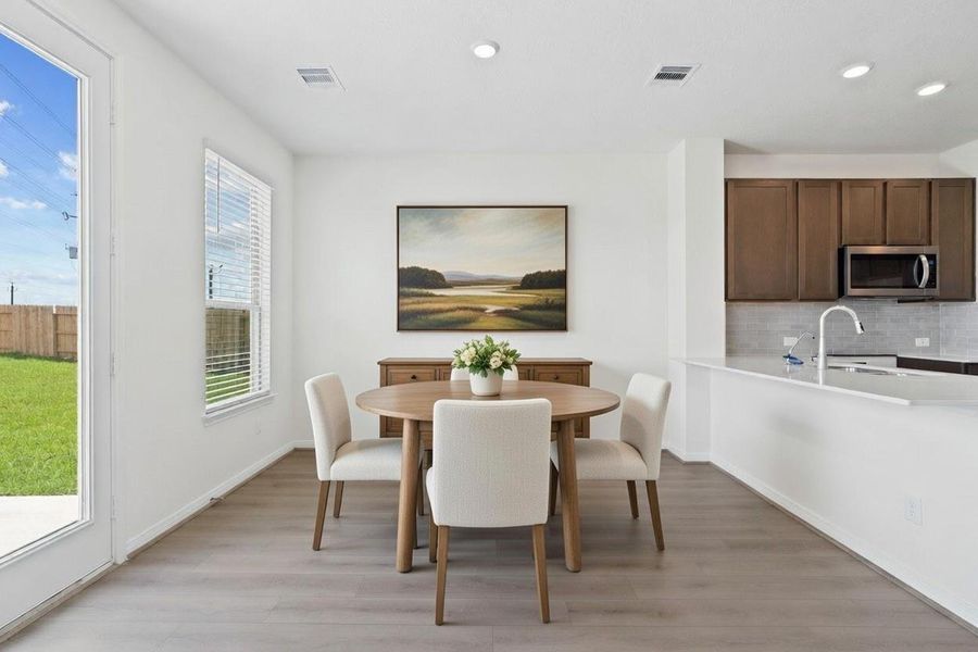 Create lasting memories around the table with family and friends in this inviting dining room! It showcases high ceilings, large window with privacy blinds, vinyl plank flooring, access door to the backyard, and recessed lighting for a warm and welcoming atmosphere.