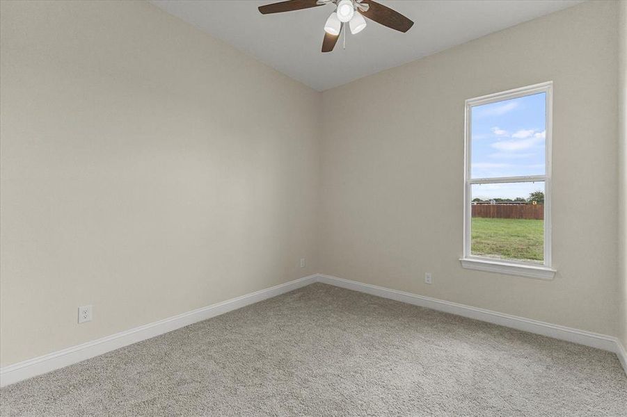 Carpeted empty room with ceiling fan and baseboards