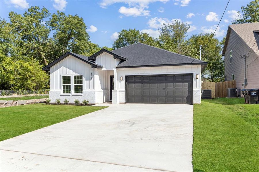 Modern inspired farmhouse featuring board and batten siding, a shingled roof, concrete driveway, and an attached garage