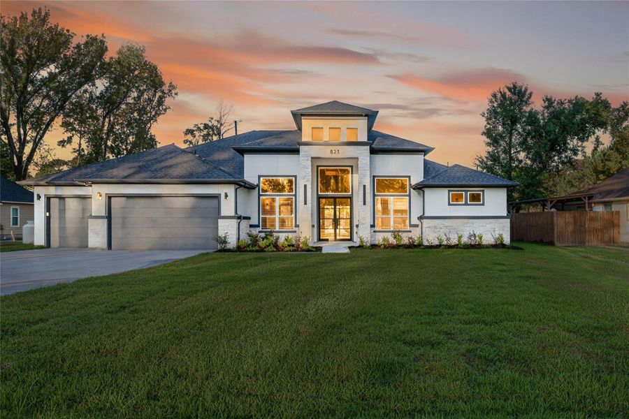 Striking contemporary exterior showcases clean architectural lines, a dramatic two-story entry, and an expansive front lawn. **Images are from a previously completed project. **
