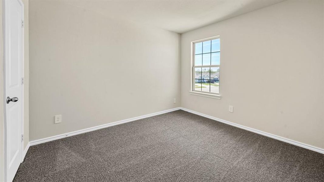 Neutral-toned room featuring a single window with grid panes, plush gray carpeting, and light-colored walls