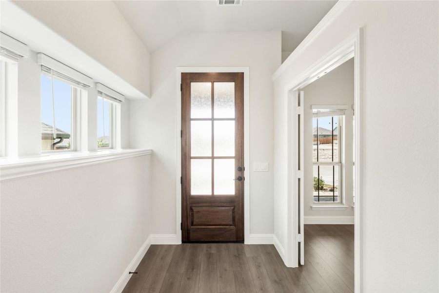 Entryway with dark wood glass-panel door, white walls, and hardwood floors Entryway with dark wood glass-panel door, white walls, and hardwood floors