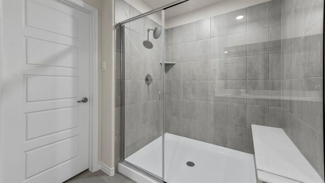 Walk-in shower with full height tile surround, dual shower heads, integrated bench, and frameless glass enclosure