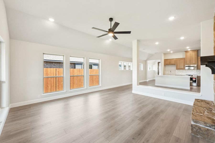 Open living room with hardwood floors, ceiling fan, and open view into kitchen with wood cabinets Open living room with hardwood floors, ceiling fan, and open view into kitchen with wood cabinets