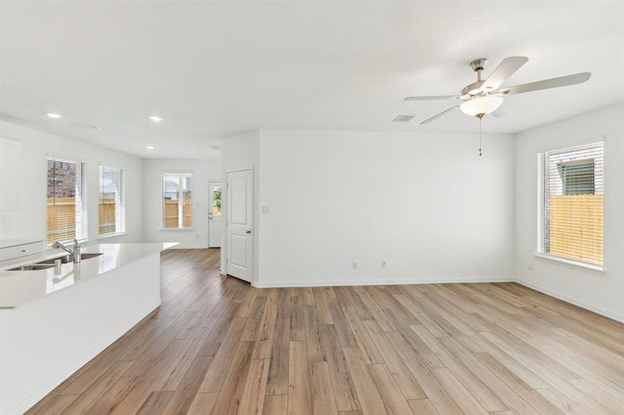 Unfurnished living room featuring light wood-type flooring, ceiling fan, and sink