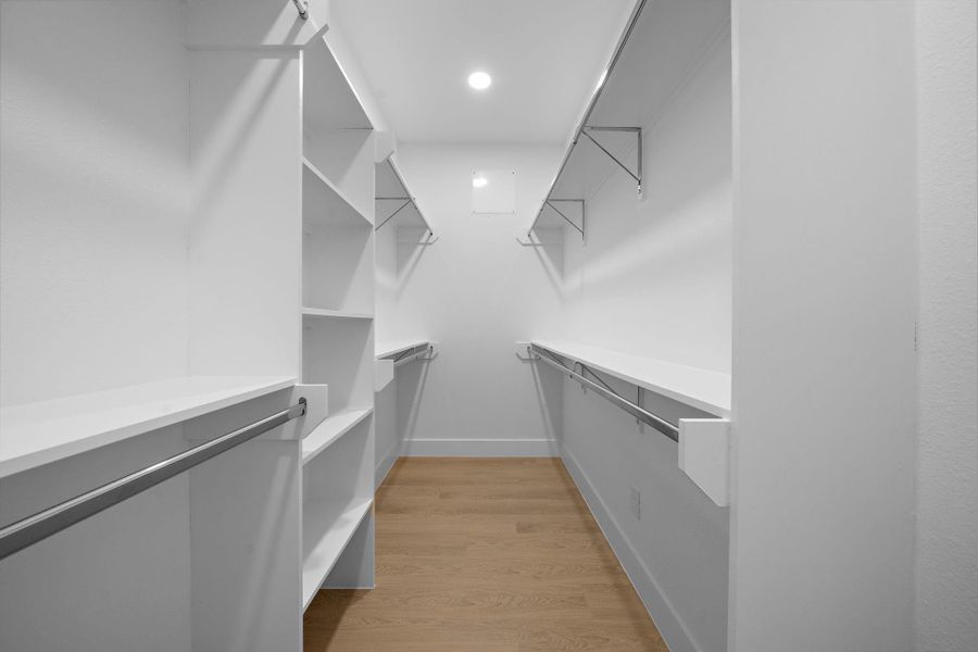This is a spacious walk-in closet with ample shelving and hanging space, featuring a clean, modern design with white walls and light LVP flooring. This is a spacious walk-in closet with ample shelving and hanging space, featuring a clean, modern design with white walls and light LVP flooring.