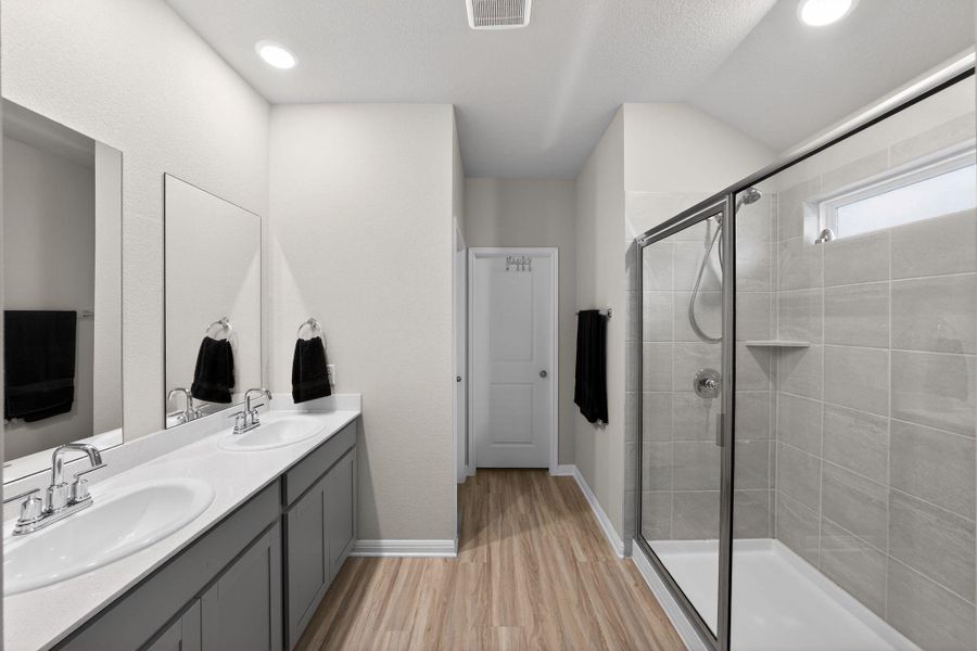 Bathroom with a stall shower, double vanity, and light wood-style floors