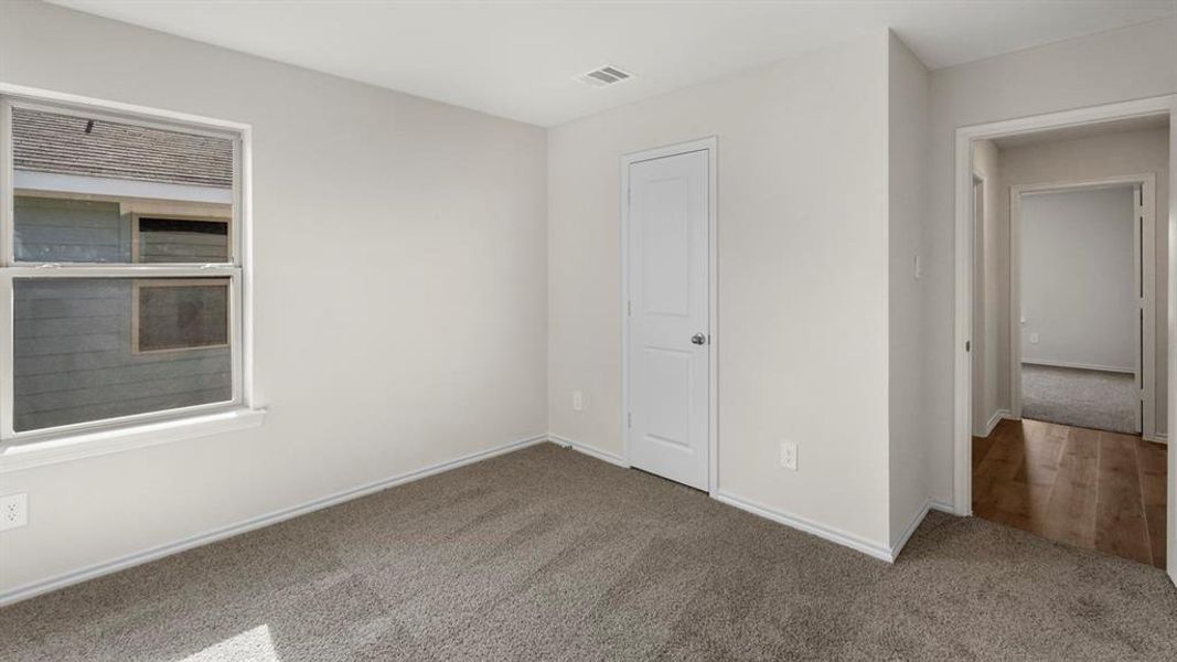 Carpeted interior room featuring a window with white trim, a solid white door, and light gray walls