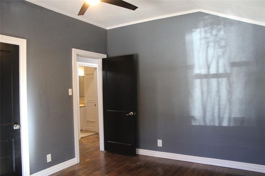 Unfurnished bedroom featuring dark wood-style flooring, crown molding, ceiling fan, and a textured wall Unfurnished bedroom featuring dark wood-style flooring, crown molding, ceiling fan, and a textured wall