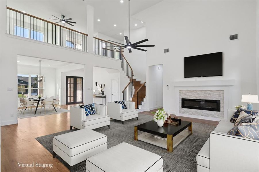 Living room with wood finished floors, recessed lighting, a fireplace, a high ceiling, and ceiling fan