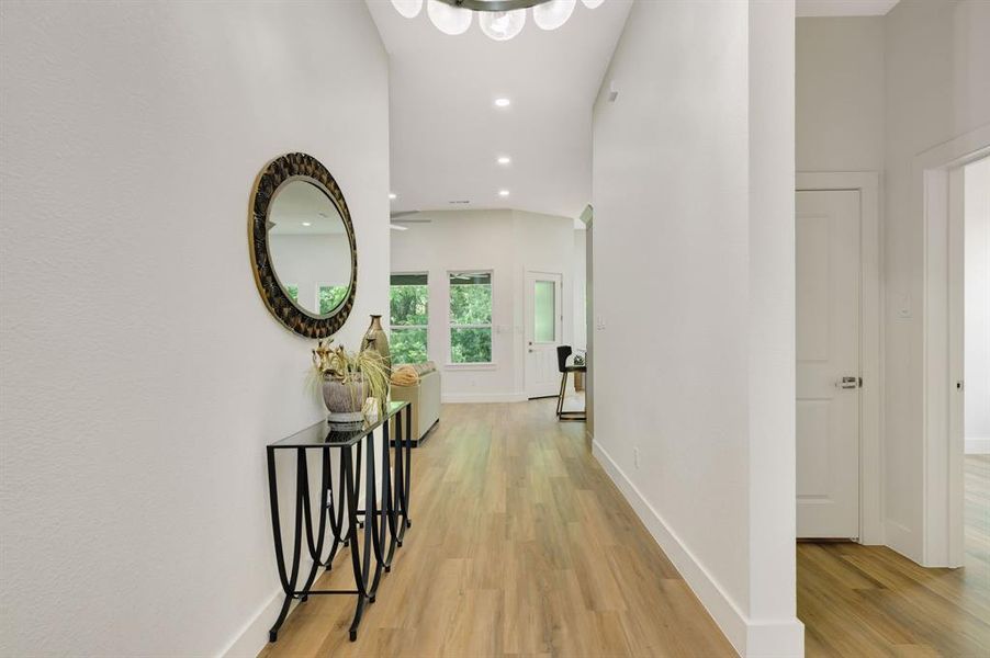 Bright hallway featuring light wood-finish flooring, recessed ceiling lighting, and crisp white walls Bright hallway featuring light wood-finish flooring, recessed ceiling lighting, and crisp white walls