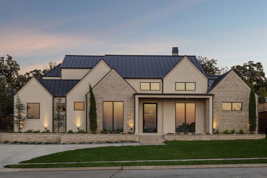 Modern farmhouse style home featuring a standing seam roof, a metal roof, stone siding, a lawn, and stucco siding Modern farmhouse style home featuring a standing seam roof, a metal roof, stone siding, a lawn, and stucco siding