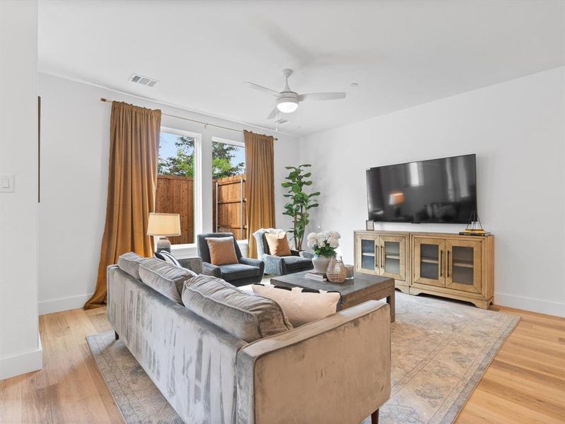 Living area featuring visible vents, light wood-style floors, ceiling fan, and baseboards