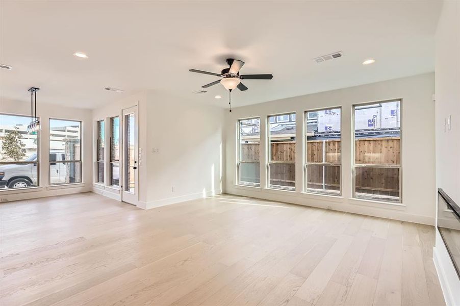 Unfurnished living room featuring plenty of natural light, ceiling fan, and light hardwood / wood-style flooring