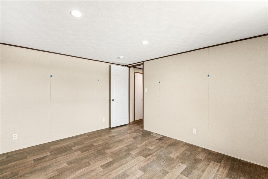 Spacious interior room featuring wood-finish flooring, recessed ceiling lighting, and light-toned wall paneling