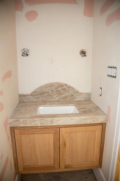 Elegantly designed white oak vanity at powder room with a Taj Mahal quartzite countertop and artistic backsplash