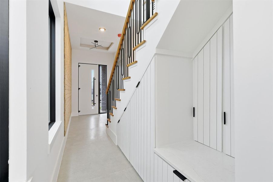 Custom vertical-slat built-ins under the stairs provide a functional storage area and bench with matching black hardware.