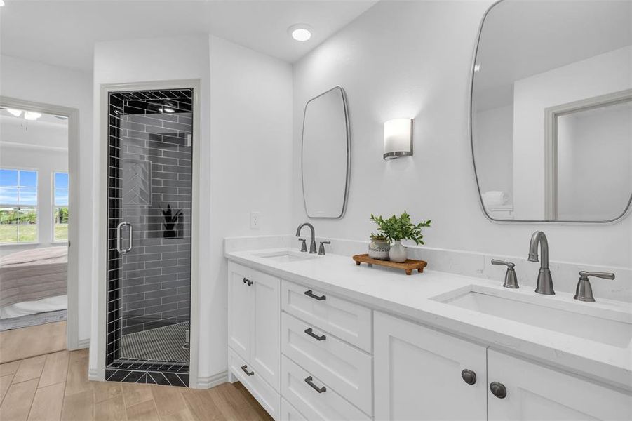 Bathroom featuring a shower stall, double vanity, light wood-type flooring, and recessed lighting Bathroom featuring a shower stall, double vanity, light wood-type flooring, and recessed lighting