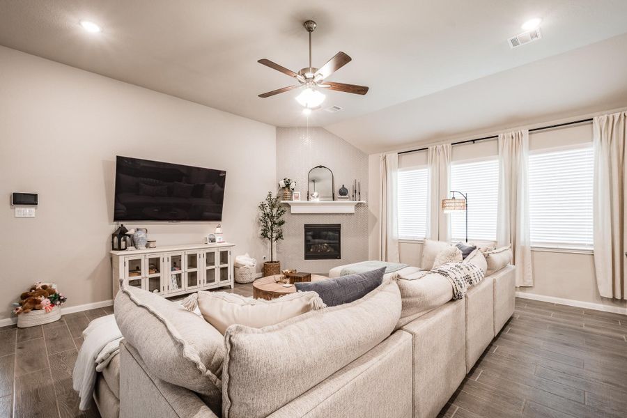 This inviting living room features a cozy sectional sofa and a modern fireplace. Large windows with curtains provide plenty of natural light, while a ceiling fan adds comfort. The neutral color palette and stylish decor create a warm, welcoming atmosphere. This inviting living room features a cozy sectional sofa and a modern fireplace. Large windows with curtains provide plenty of natural light, while a ceiling fan adds comfort. The neutral color palette and stylish decor create a warm, welcoming atmosphere.