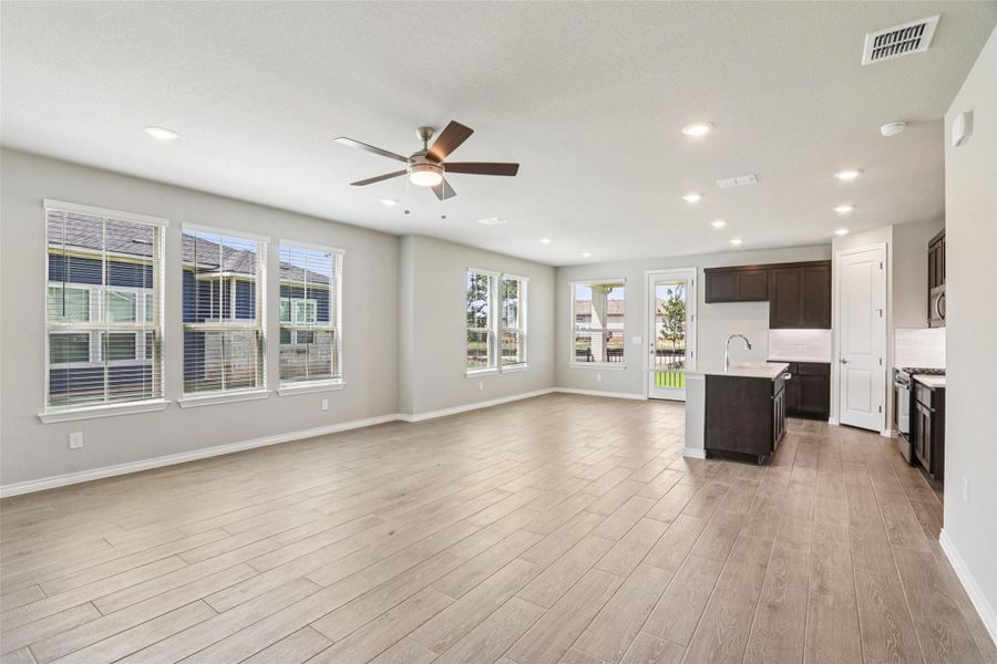 Unfurnished living room featuring healthy amount of natural light, a ceiling fan, light wood-style floors, and recessed lighting
