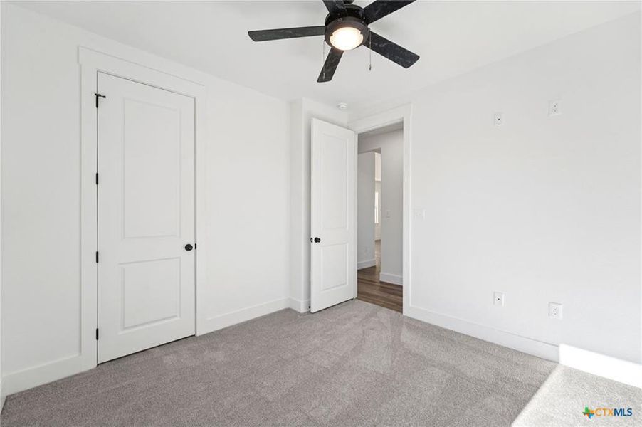 A well-lit bedroom with neutral carpet and a modern ceiling fan for ultimate comfort. A well-lit bedroom with neutral carpet and a modern ceiling fan for ultimate comfort.