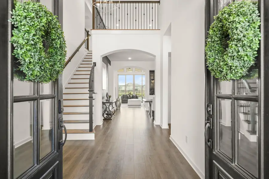 The elegant foyer greets you through the double door entry with gorgeous Revwood waterproof flooring, 20-foot ceilings, a beautiful chandelier and the stairway has hardwood treads and decorative wrought iron spindles.