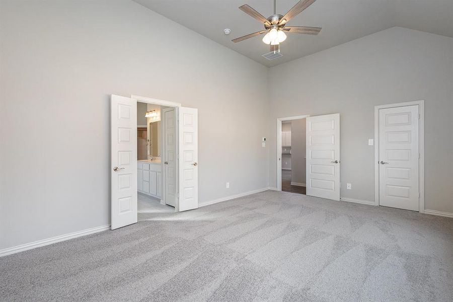 Unfurnished bedroom with ceiling fan, a closet, high vaulted ceiling, and light colored carpet