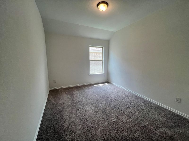 Carpeted empty room featuring lofted ceiling and baseboards