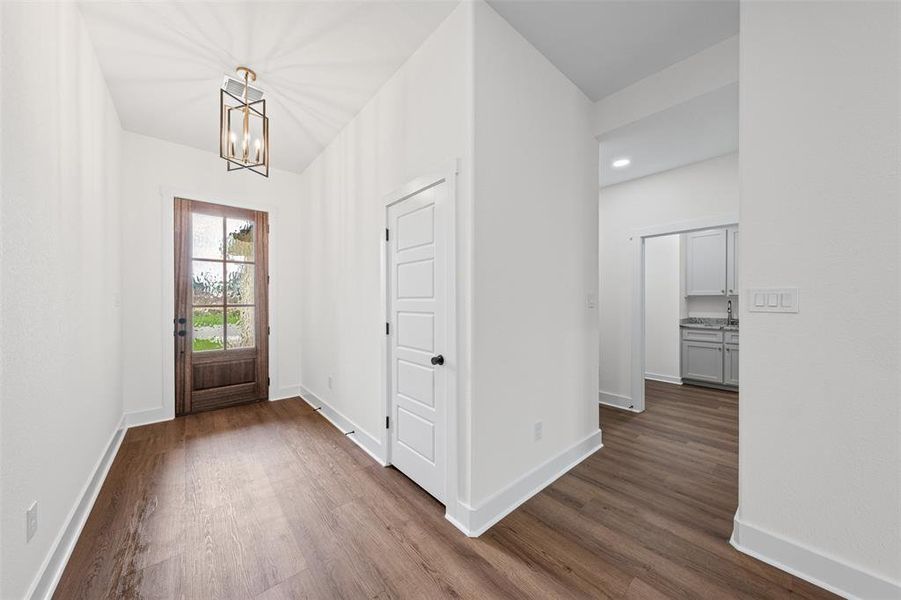 Entryway featuring hardwood floors, a wooden front door with glass panels, a decorative overhead light fixture, and white walls with white trim