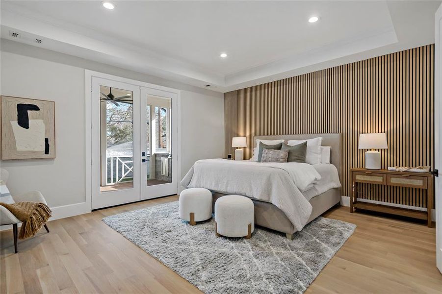 Primary bedroom features paneled accent wall and French doors