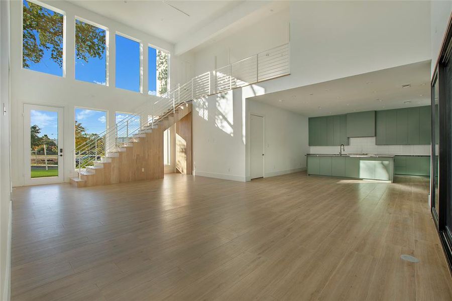 Unfurnished living room featuring light hardwood / wood-style floors, a towering ceiling, and sink