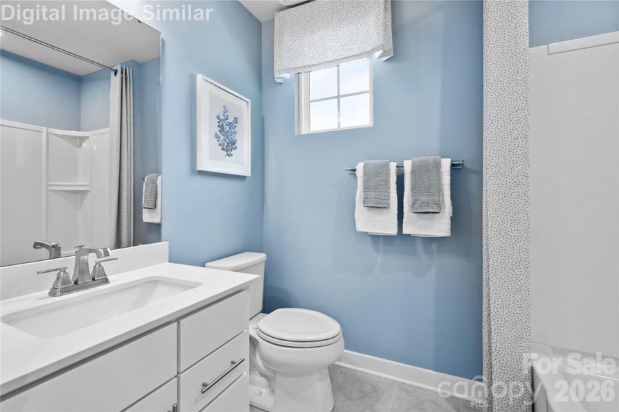 Bright shared bathroom with a sunlit window, full-size tub, and a large mirror—blending function and style for everyday comfort.