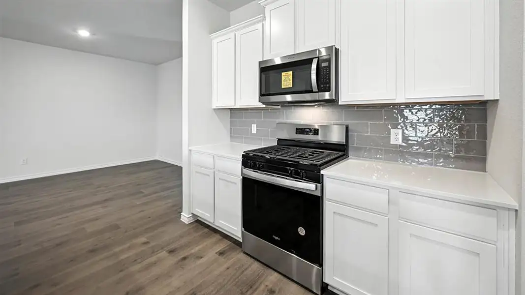 Kitchen featuring white shaker-style cabinetry, stainless steel appliances, a gas range, white countertops, and a gray subway tile backsplash Kitchen featuring white shaker-style cabinetry, stainless steel appliances, a gas range, white countertops, and a gray subway tile backsplash