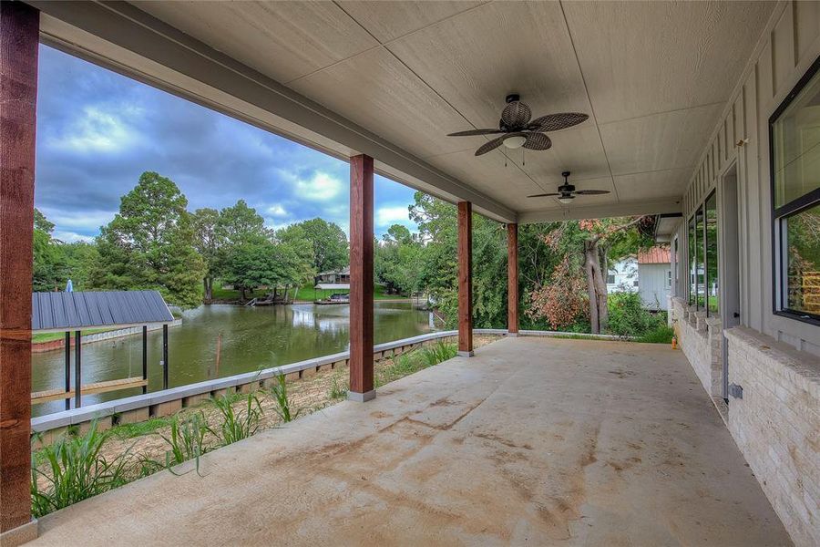 View of patio with a water view, ceiling fan, and a dock View of patio with a water view, ceiling fan, and a dock
