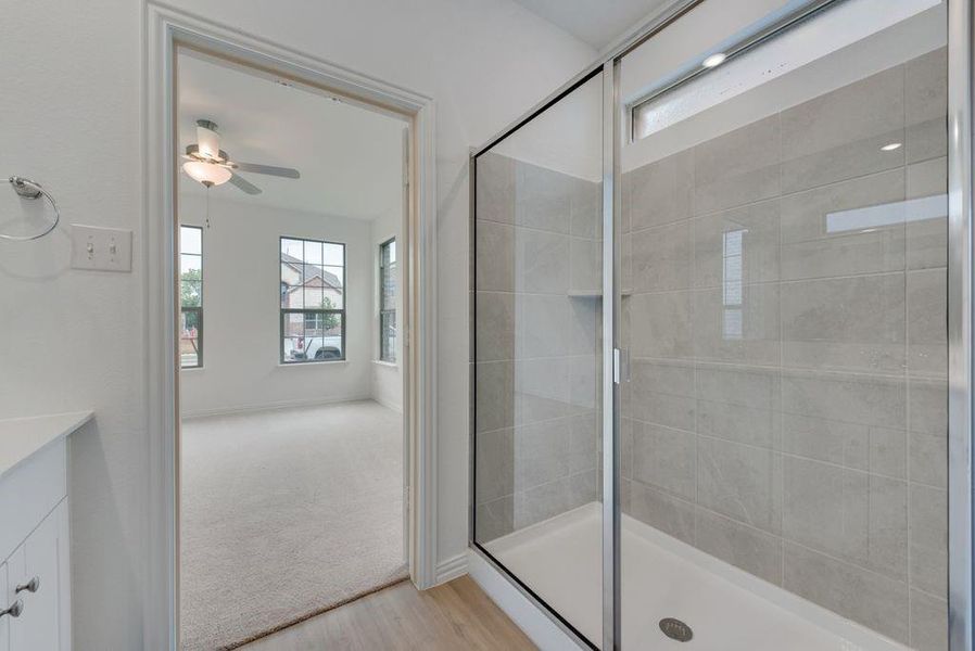 Bathroom with wood finished floors, plenty of natural light, ceiling fan, and a shower stall Bathroom with wood finished floors, plenty of natural light, ceiling fan, and a shower stall