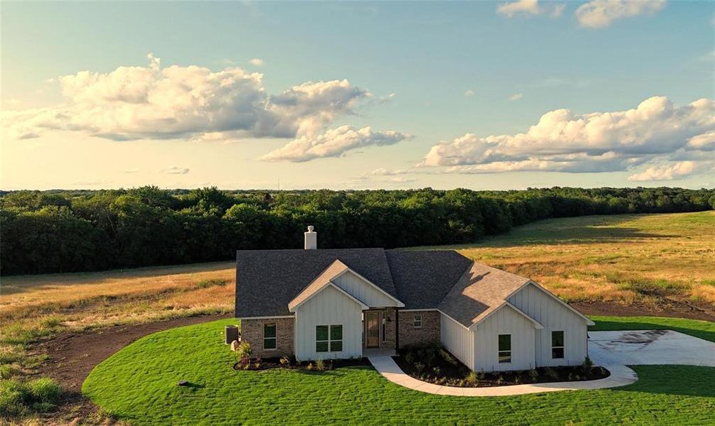View of front of home featuring a chimney, a shingled roof, stone siding, and a front lawn