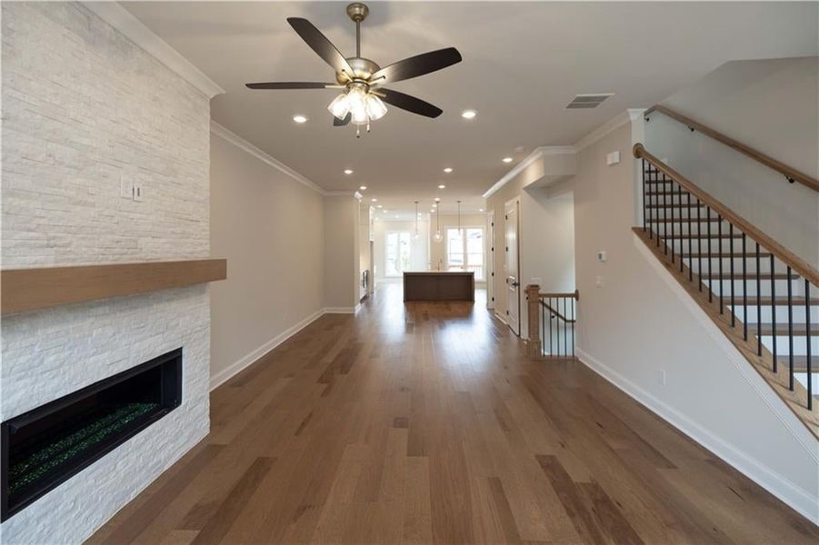 Unfurnished living room with crown molding, a fireplace, dark hardwood / wood-style floors, and ceiling fan