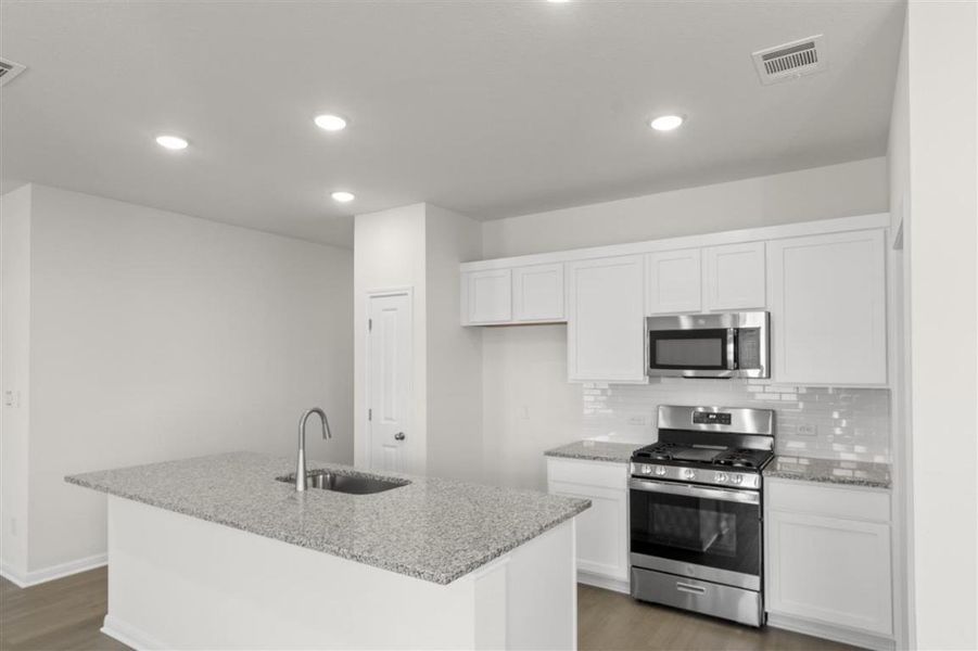 Kitchen featuring visible vents, white cabinets, a sink, stainless steel appliances, and backsplash