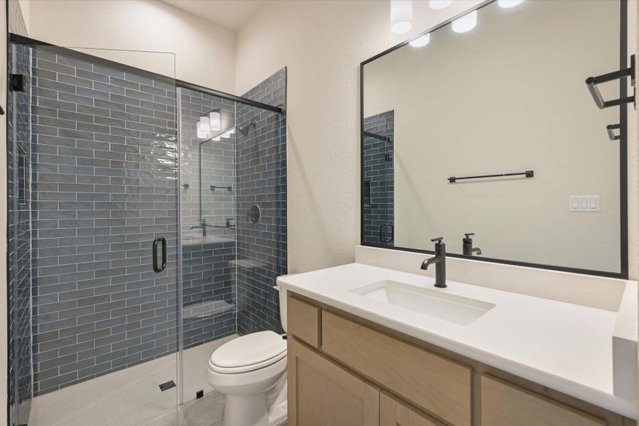 A well-appointed bathroom features a spacious glass-enclosed shower and a modern vanity with a single basin sink.