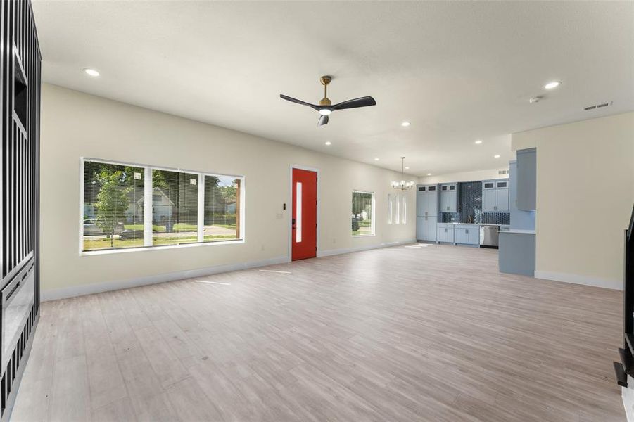 Unfurnished living room featuring recessed lighting, ceiling fan, light wood-type flooring, and a chandelier